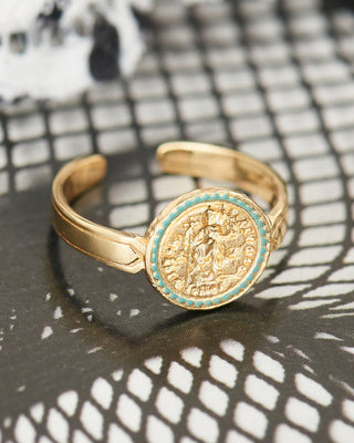 Gold ring with a coin design on a textured surface