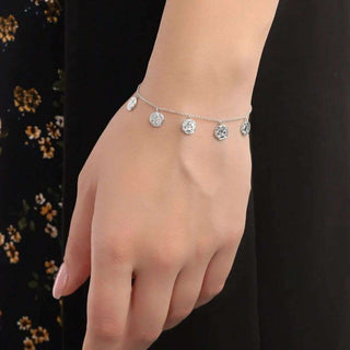 Silver bracelet with round charms on a wrist against a dark background
