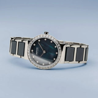 Silver watch with black ceramic links on a light blue background