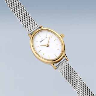 Gold and silver watch with mesh band on a light gray background