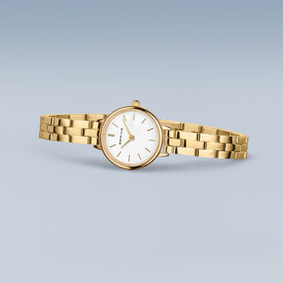 Gold watch with a white face on a light gray background