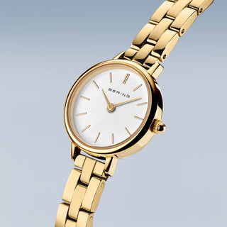 Gold watch with a white face on a light gray background