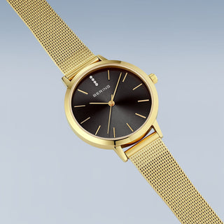 Gold watch with a black face on a light gray background