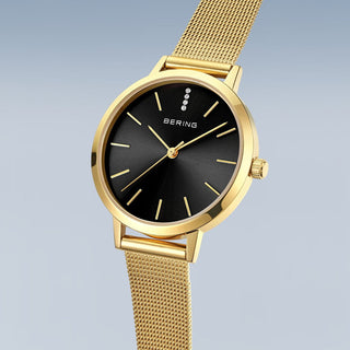 Gold watch with black face on a light gray background