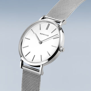Silver watch with mesh band on a light gray background