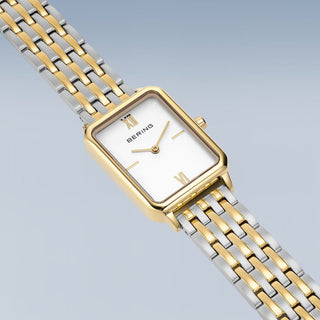 Gold and silver watch with Bering brand on a light gray background