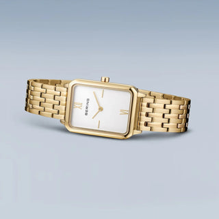 Gold watch with a white face on a light gray background