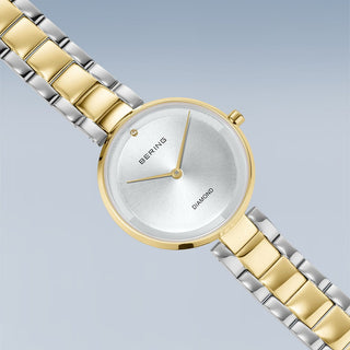 Two-tone gold and silver watch with Bering brand on a light gray background