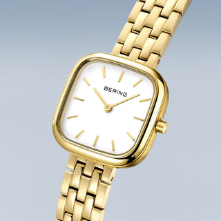 Gold watch with white face on a light gray background
