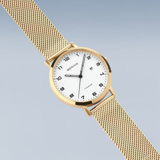 Gold watch with a white face on a light gray background