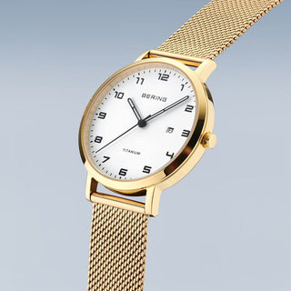 Gold watch with a white face on a light gray background