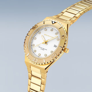 Gold wristwatch with a white dial on a light gray background