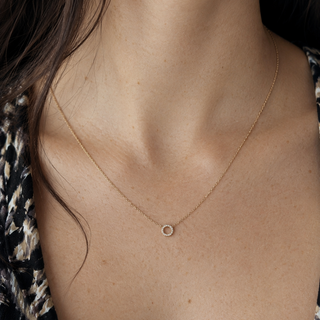 Gold necklace with a small round pendant on a person's neck