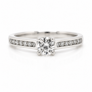 A 18ct white gold diamond engagement ring with a round-cut center stone and small pavé diamonds along the band, shown on a clean white background.