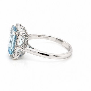 A silver ring featuring a marquise-cut light blue gemstone in an ornate filigree setting, shown from a side angle on a white background.