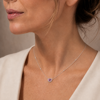 Close-up of a woman wearing a necklace with a purple pendant against a neutral background