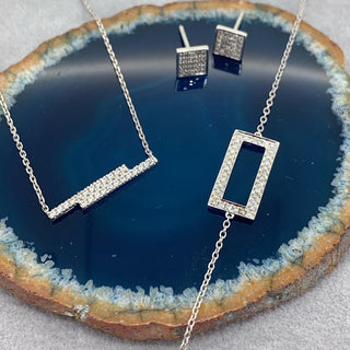 Silver jewelry set with necklace and earrings on a blue stone surface