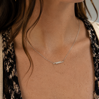 Close-up of a person wearing a delicate silver necklace with a subtle design.