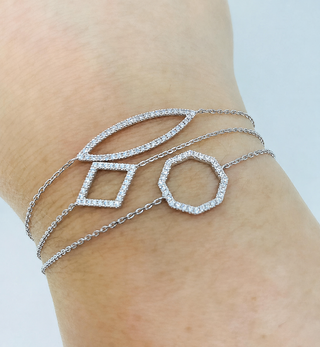 Silver bracelet with geometric designs on a wrist against a light background