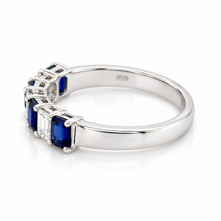 A silver-colored ring featuring a row of rectangular blue sapphires and clear baguette and round diamonds, shown on a clean white background.
