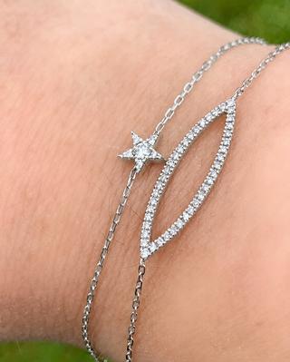 Silver bracelet with star and circle design on a wrist against a natural background