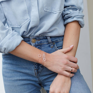 Person wearing a bracelet and ring with a light blue shirt and jeans.