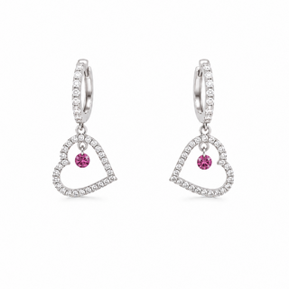 A pair of silver huggie hoop earrings with dangling open heart charms. The heart charms are outlined with small clear pavé stones and feature a central round pink gemstone, set against a plain white background.