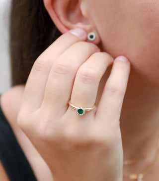Close-up of a person wearing a green gemstone ring and earrings.