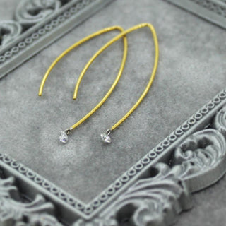 Yellow earrings with small clear stones on a decorative gray surface