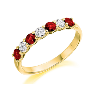 A yellow gold eternity ring featuring alternating round-cut red rubies and clear round-cut diamonds, set against a clean white background.