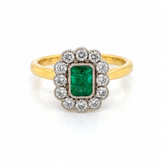 A yellow gold ring featuring a central rectangular emerald-cut green gemstone surrounded by a halo of round clear stones, set on a plain white background.