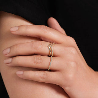 Close-up of a hand wearing a gold ring on a dark background
