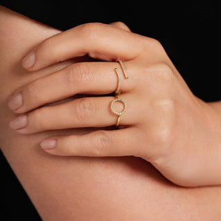 Close-up of a hand wearing two gold rings on a dark background