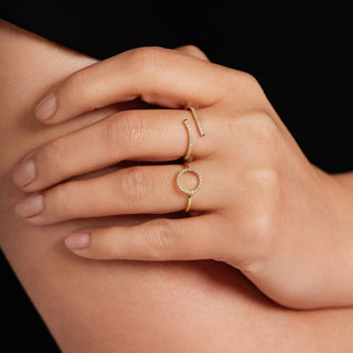 Close-up of a hand wearing two gold rings on a dark background