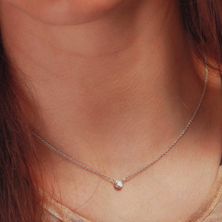 Close-up of a 9ct Goldnecklace with a small round pendant on a person's neck.