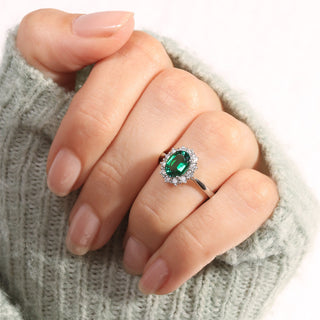 Hand wearing a ring with a green gemstone on a textured surface