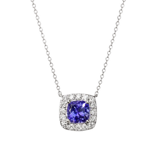 A silver-toned necklace featuring a cushion-cut tanzanite pendant surrounded by a halo of small clear stones, suspended from a delicate silver chain against a light gray background.