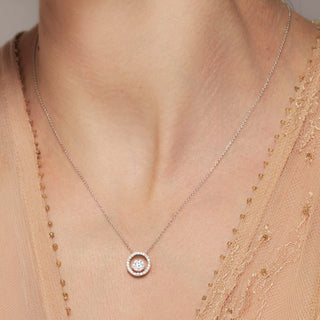 Necklace with a circular pendant worn by a person against a neutral background