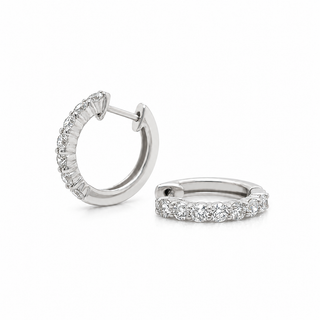 A pair of white gold huggie hoop earrings with pavé-set diamond stones, shown on a clean white background.