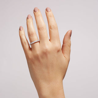 Hand wearing a diamond eternity ring on a plain background