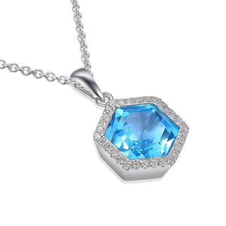A white gold hexagonal pendant necklace featuring a large faceted light blue gemstone surrounded by a halo of small clear stones, shown on a white background.