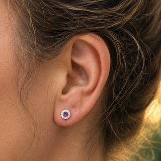 Close-up of an ear wearing a purple gemstone stud earring.