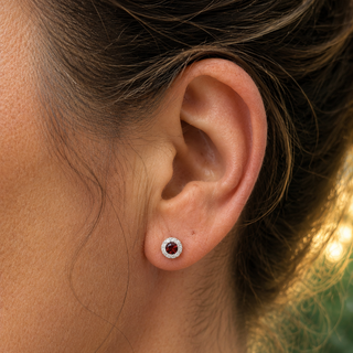 Close-up of an ear wearing a stud earring with a red gemstone.
