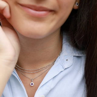 Close-up of a person wearing multiple necklaces with purple gemstones.