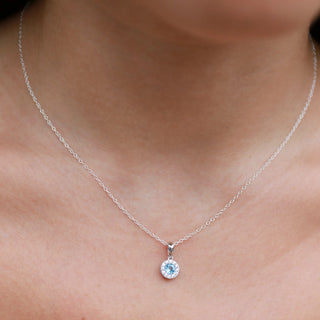 9ct gold necklace with a round aquamrine pendant on a person's neck