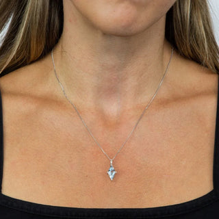 Silver necklace with a pendant on a person wearing a black top.