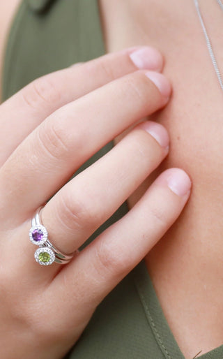 Close-up of a hand wearing a silver ring with colored gemstones.