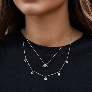 Necklace with 'AR' pendant on a person wearing a black shirt