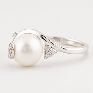 Silver ring with a pearl and small diamonds on a light gray background