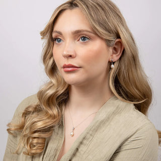 Woman with blonde hair wearing a beige top against a plain background